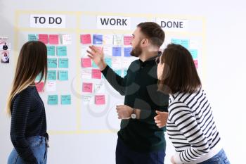 Young business people near scrum task board in office�