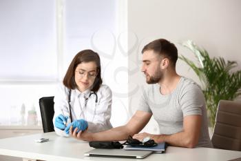 Doctor taking blood sample of diabetic patient in clinic�