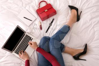 Young businesswoman with laptop sitting on bed�