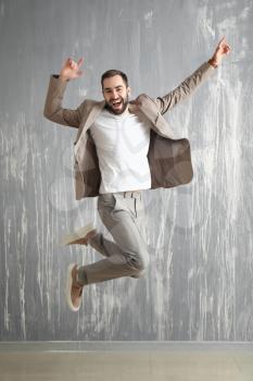 Handsome fashionable man jumping against grunge wall�