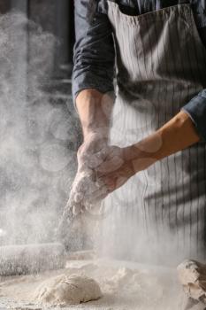Young man preparing dough for bread in kitchen�