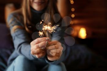 Young woman with sparkler at home�