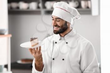 Male confectioner with piece of tasty cake in kitchen�