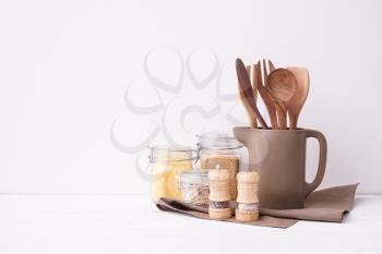 Set of kitchen utensils with groats on table near white wall�
