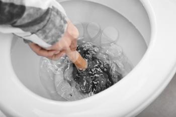 Young woman using plunger to unclog a toilet bowl�