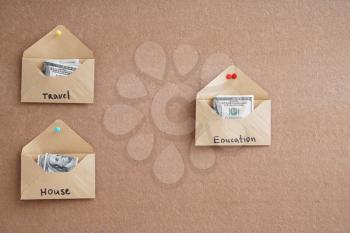 Envelopes with money for different needs on color background. Concept of savings�