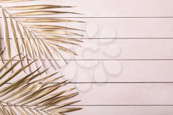 Painted golden tropical leaves on wooden background�