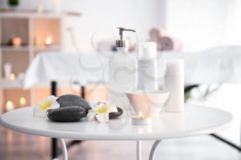 Massage stones with cosmetics products on table in spa salon�