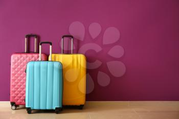 Packed suitcases near color wall�