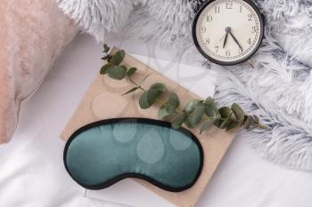 Sleep mask, notebooks and clock on bed�