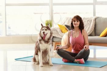 Young woman with her cute dog practicing yoga at home�