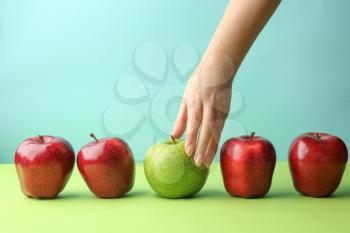 Female hand with tasty apples on color background. Concept of uniqueness�