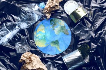 Paper figure of earth and garbage on polyethylene film. Concept of environmental protection�