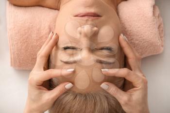 Mature woman receiving face massage in beauty salon�
