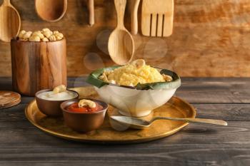 Bowl with traditional Indian food pongal on wooden table�