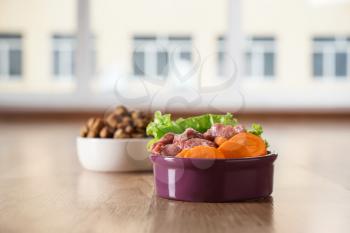 Bowls with dry and fresh pet food on floor�