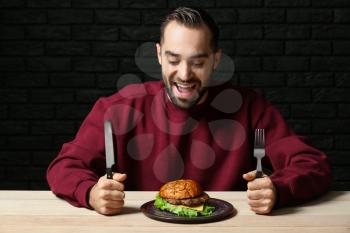 Man with tasty burger at table�