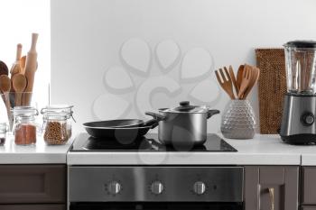 Modern electric stove and utensils in kitchen�
