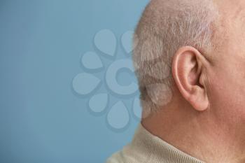 Senior man with hearing problem on color background, closeup�