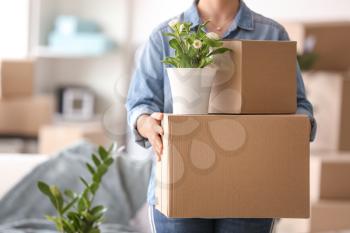 Woman with moving boxes and plant in room�