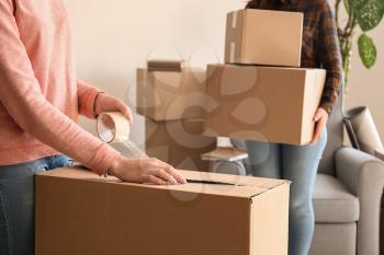 Young woman packing belongings in room�