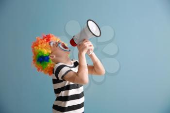 Cute little boy with clown makeup and megaphone on color background. April fools' day celebration�