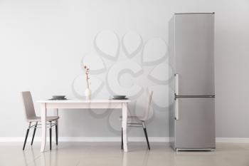 Modern fridge and served table in kitchen�