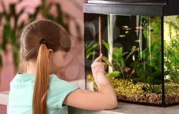 Cute little girl looking at fish in aquarium�