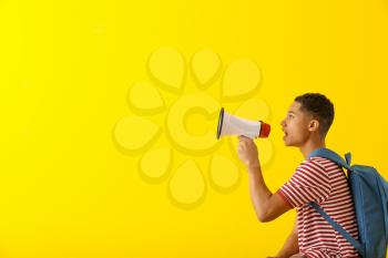 Portrait of African-American teenage boy with megaphone on color background�