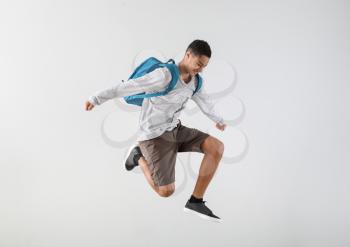 Portrait of jumping African-American teenage boy on grey background�