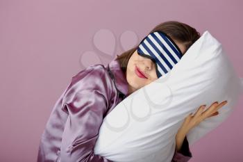 Sleepy woman with mask and pillow on color background�