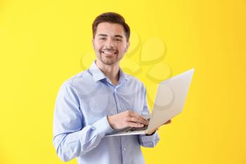 Male programmer with laptop on color background�