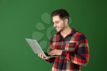 Male programmer with laptop on color background�
