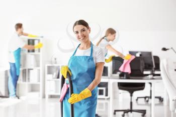 Female janitor with vacuum cleaner in office�