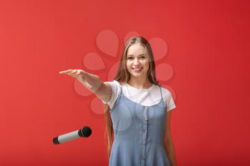Beautiful woman dropping microphone on color background�