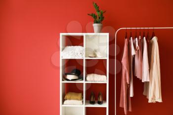 Rack with stylish clothes and shoes on color background�