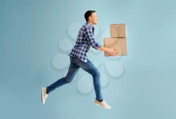 Jumping young man with boxes on grey background�