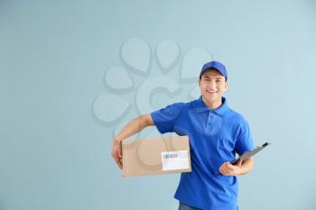 Delivery man with box on color background�