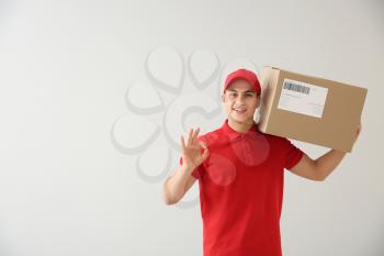 Delivery man with box showing OK on white background�