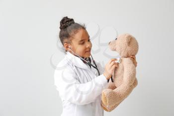 Portrait of little African-American doctor on white background�