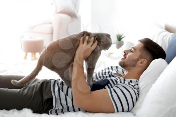 Young man with cute funny cat at home�