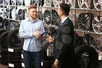 Seller helping man to choose disks and tires in car store�