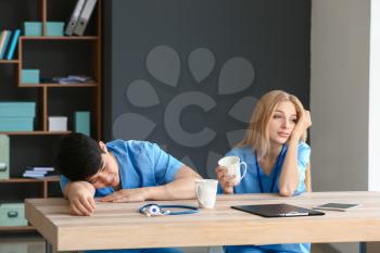 Tired medical assistants at table in clinic�
