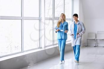 Male doctor and female medical assistant walking down the corridor in clinic�