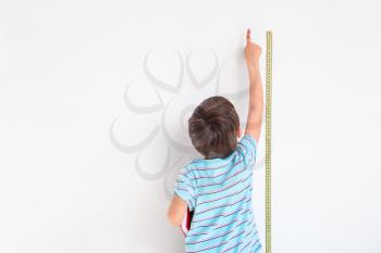 Cute little boy measuring height near wall�