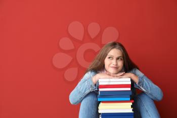 Beautiful young woman with books on color background�