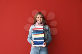 Beautiful young woman with books on color background�