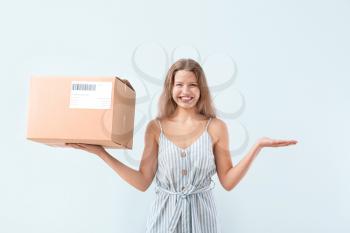 Happy woman with cardboard box on light background�