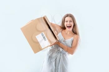 Happy woman with cardboard box on light background�