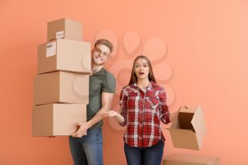 Young couple with many cardboard boxes on color background�